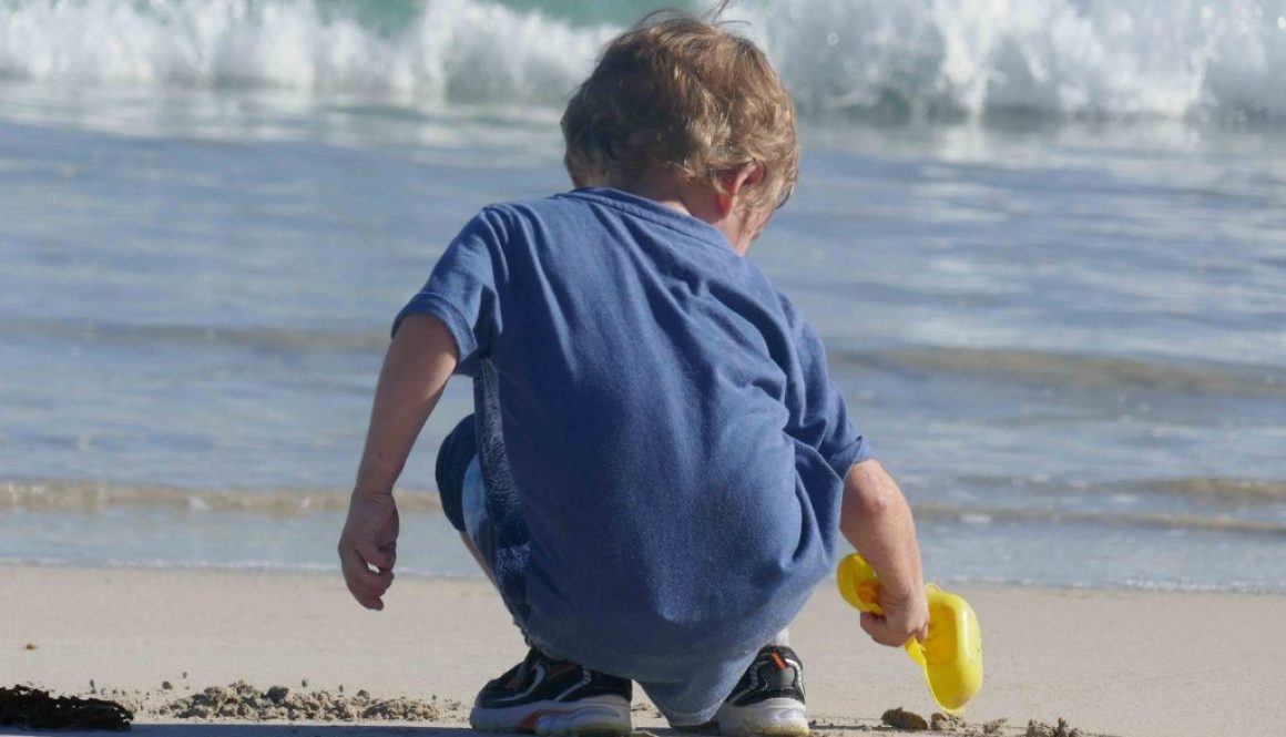 https://www.writteninwaikiki.com/10-tips-taking-better-photos-kids/ child beach digging in the sand