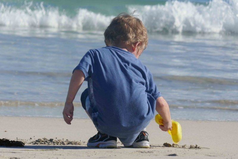 https://www.writteninwaikiki.com/10-tips-taking-better-photos-kids/ child beach digging in the sand