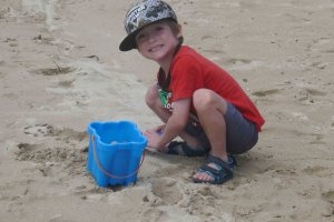 how to build self-esteem in kids boy child playing in sand at the beach