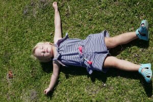 how to build self-esteem in kids toddler girl lying on grass
