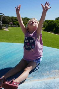 girl with arms up at park shirt says 'wake up be happy"