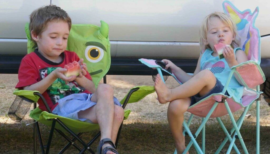 kids sitting on camp chairs on a camping trip