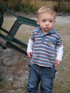 boy toddler standing next to a fallen chair