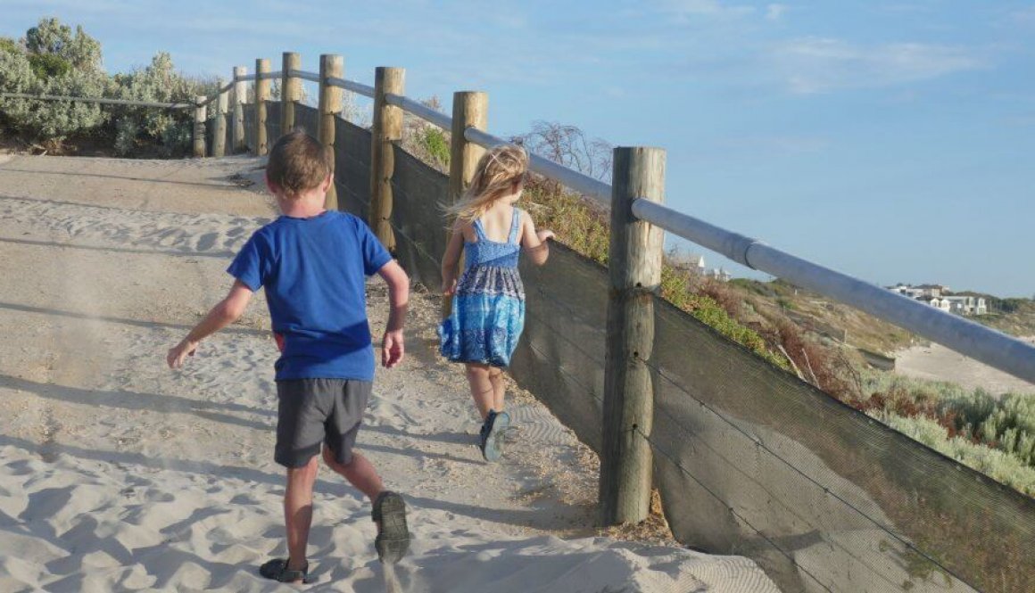 kids making memories running up hill from the beach