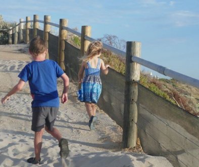 kids making memories running up hill from the beach