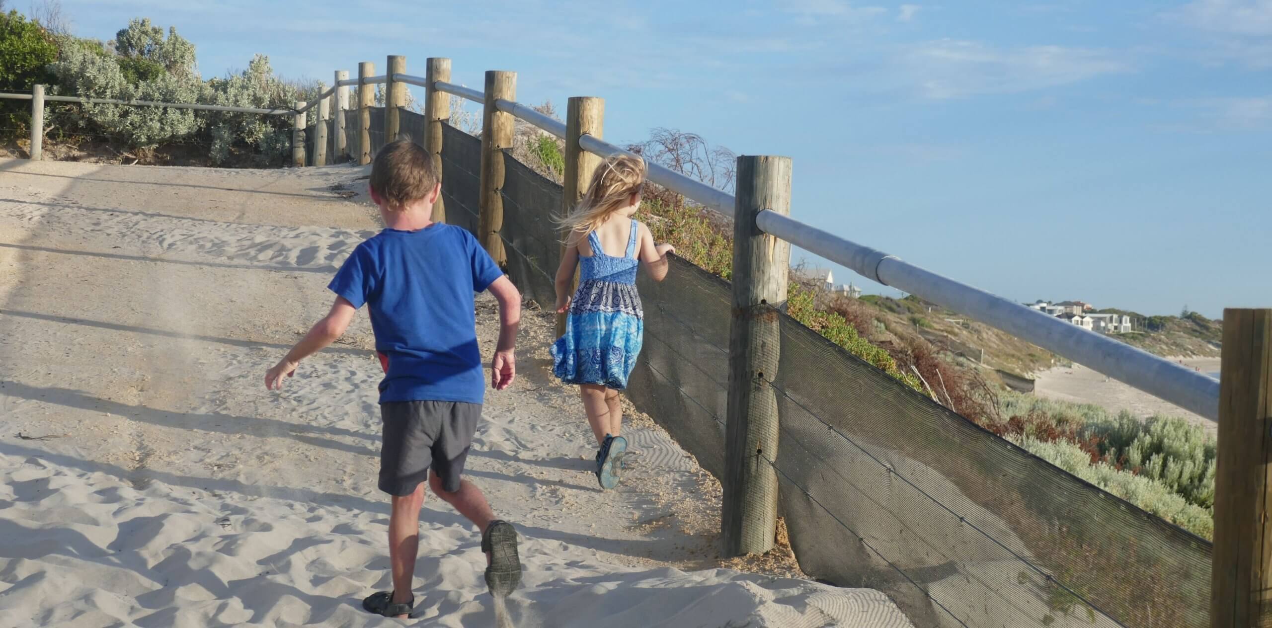 kids making memories running up hill from the beach